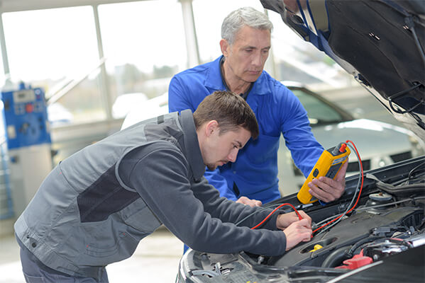 Schüler mit Lehrer beim Reparieren eines Fahrzeugs